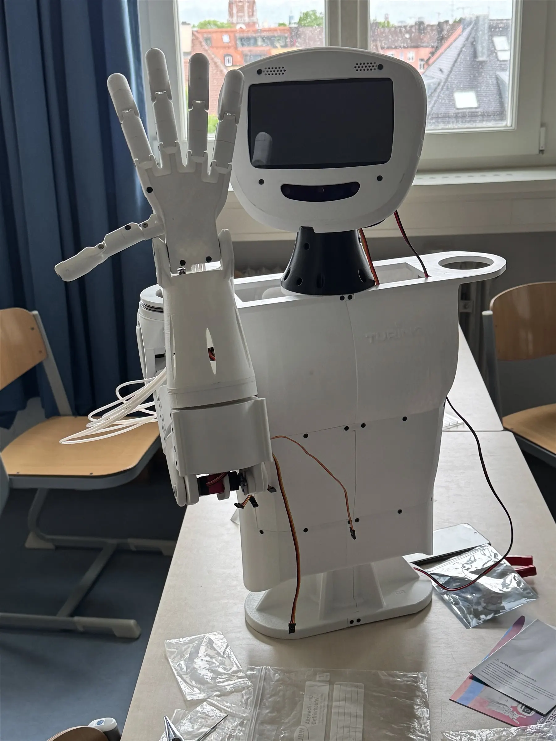 Der im Pluskurs Robotic gebaute humanoide Roboter „Turing“ aus dem 3D-Drucker, mit erhobener Hand