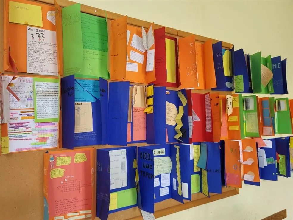 Bunte, selbst gestaltete Lapbooks der Klasse 5b an einer Pinnwand