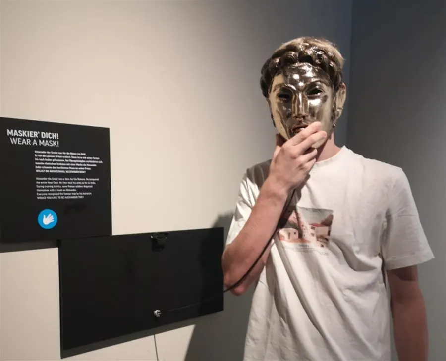 Ein Schüler hält sich im Museum eine goldene Maske vors Gesicht