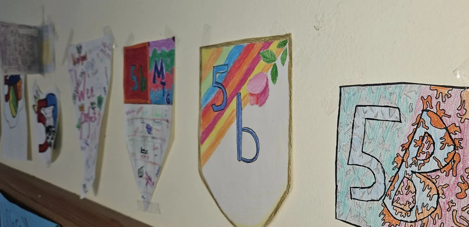 Selbstgestaltete Klassenwappen einer fünften Klasse an der Wand des Klassenzimmers