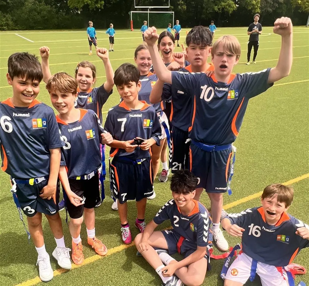 Jubelnde Flag-Football-Mannschaft des MTG in Trikots auf dem Kunstrasen