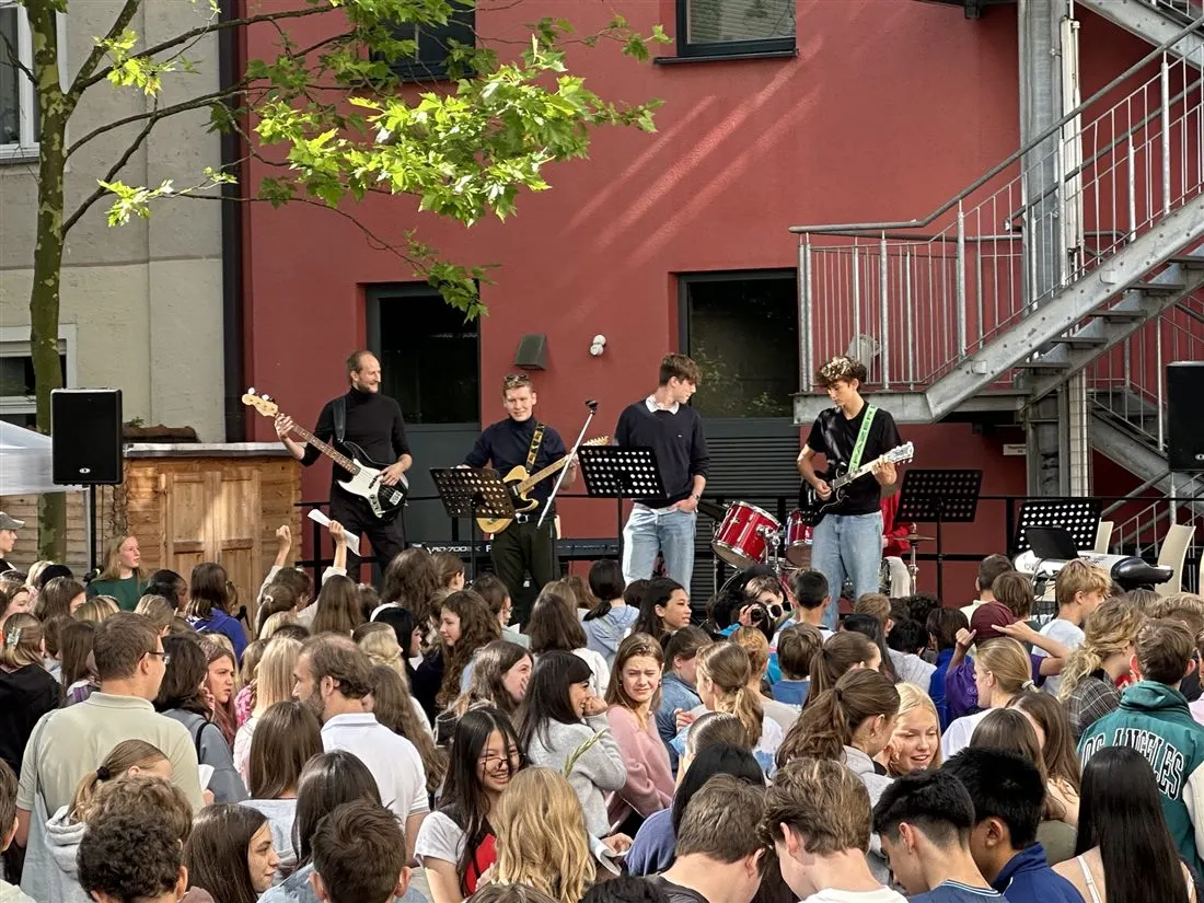 Schülerband spielt auf der Bühne im Hof vor dichtem Publikum