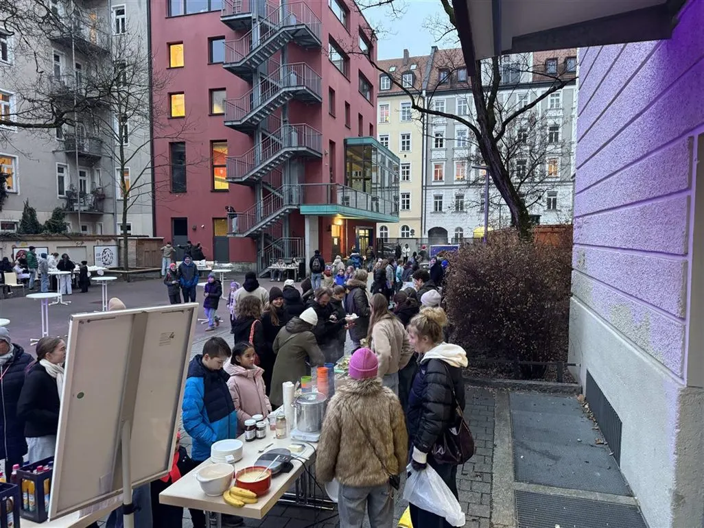 Adventsbasar im Pausenhof in der Dämmerung, Stände mit Crêpes und warmen Getränken
