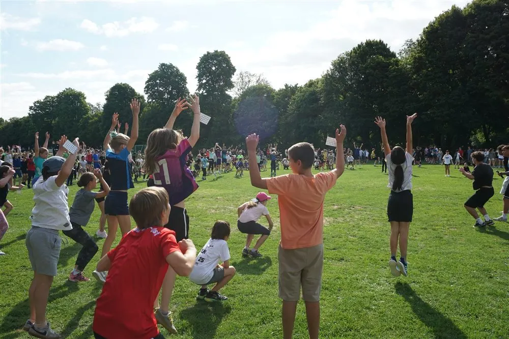 Jubelnde Schülerinnen und Schüler mit erhobenen Armen auf der Wiese