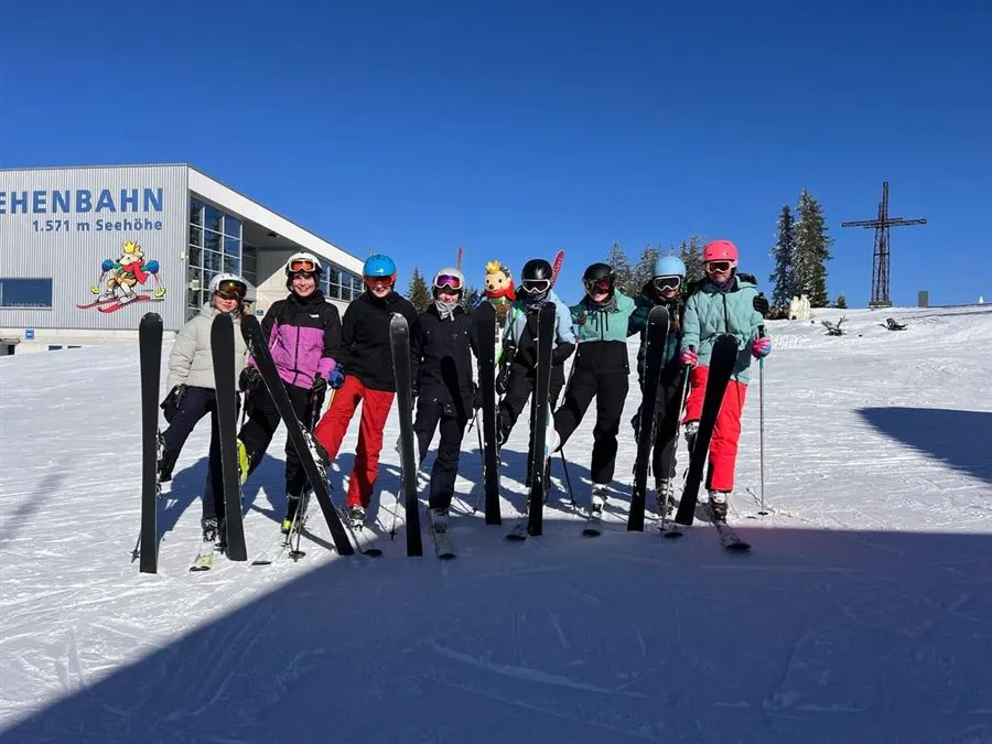 Schülergruppe mit Ski bei der Wintersportwoche in den Bergen
