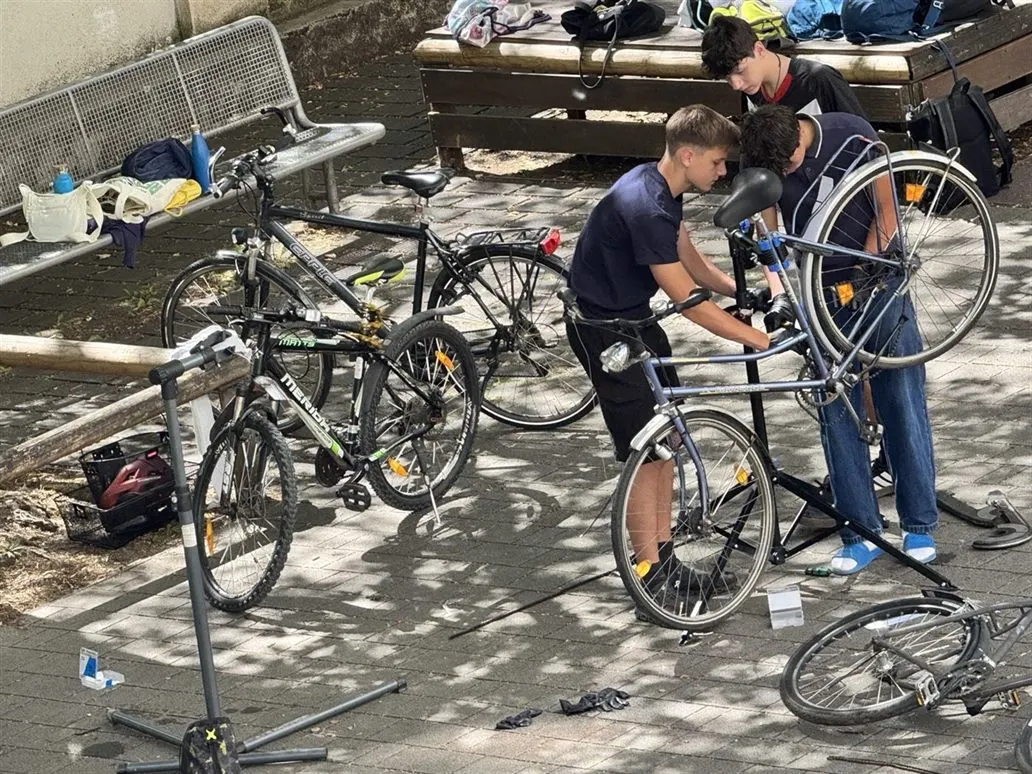 Jugendliche reparieren Fahrräder an Montageständern im Pausenhof