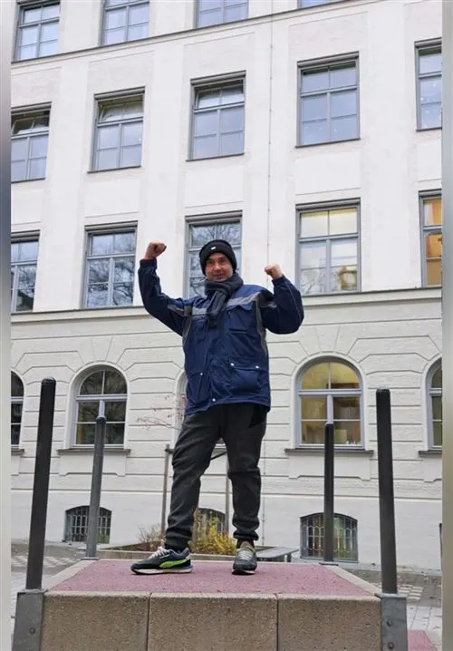 Sabino Ziccolella von der technischen Hausverwaltung steht auf einem Sockel vor dem Schulhaus und reckt beide Fäuste in die Höhe