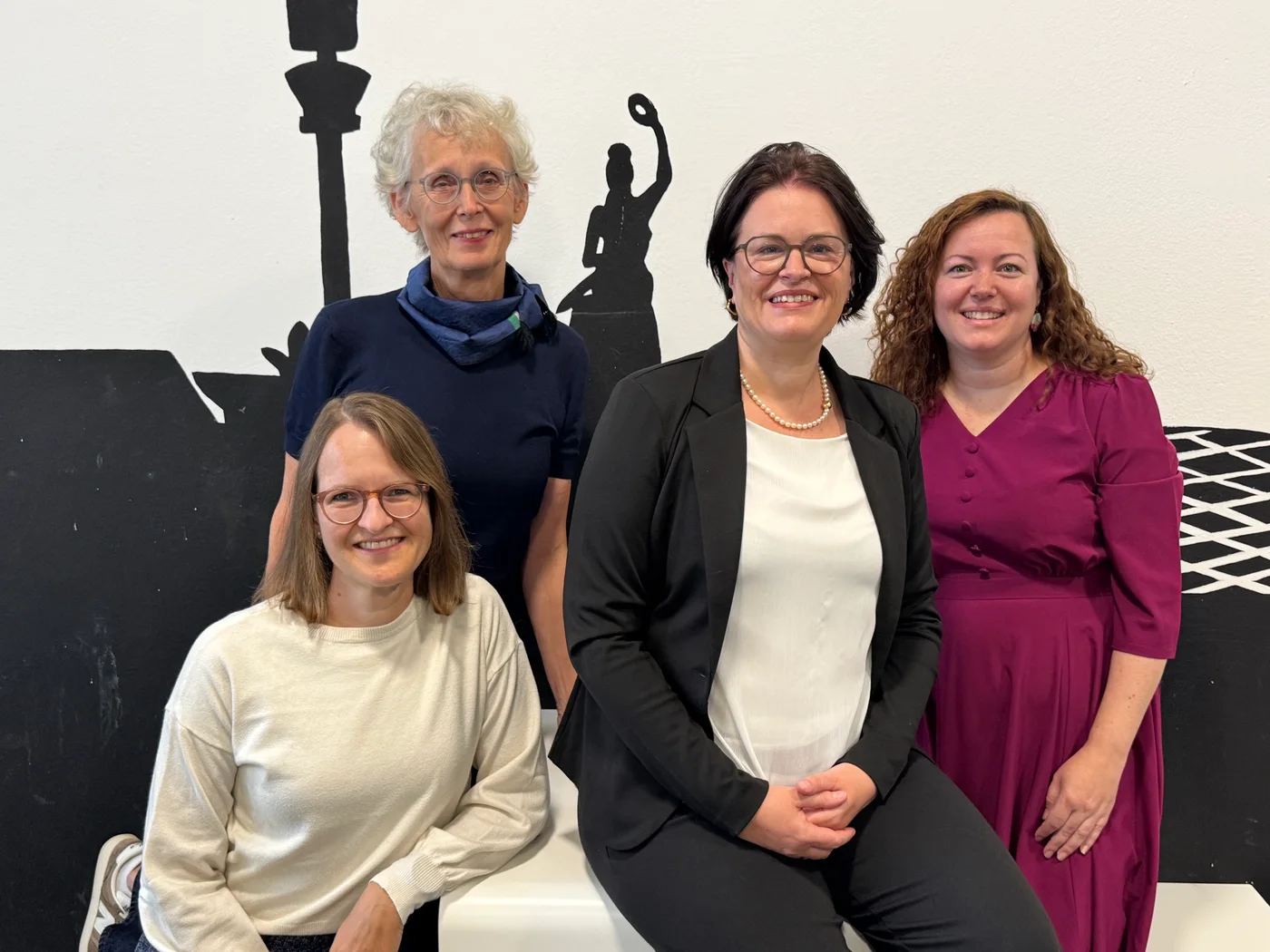 Die vier Mitglieder des Schulleitungsteams vor dem Wandbild im Schulhaus